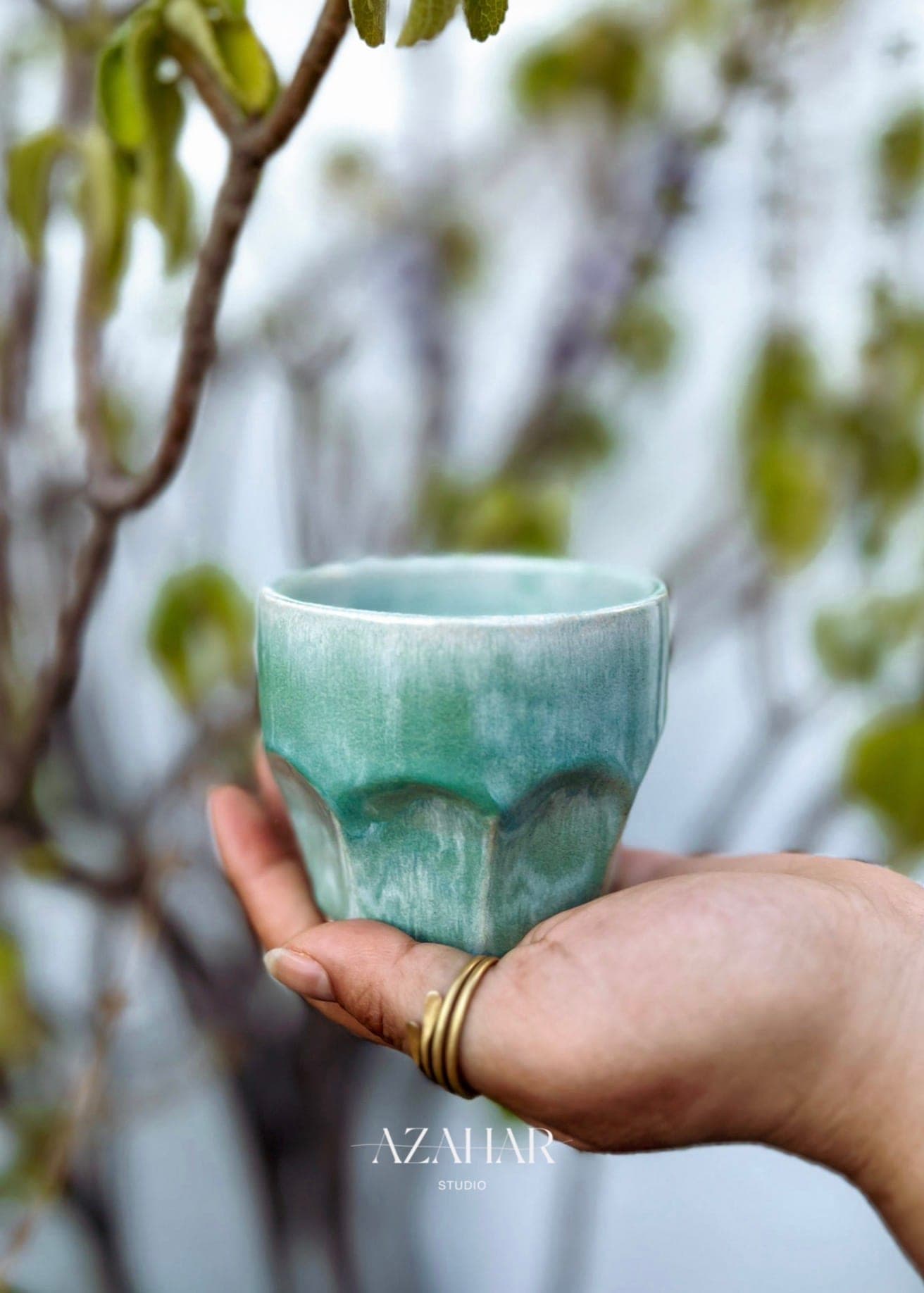 Hand hält eine glasierte Keramiktasse von Azahar Studio